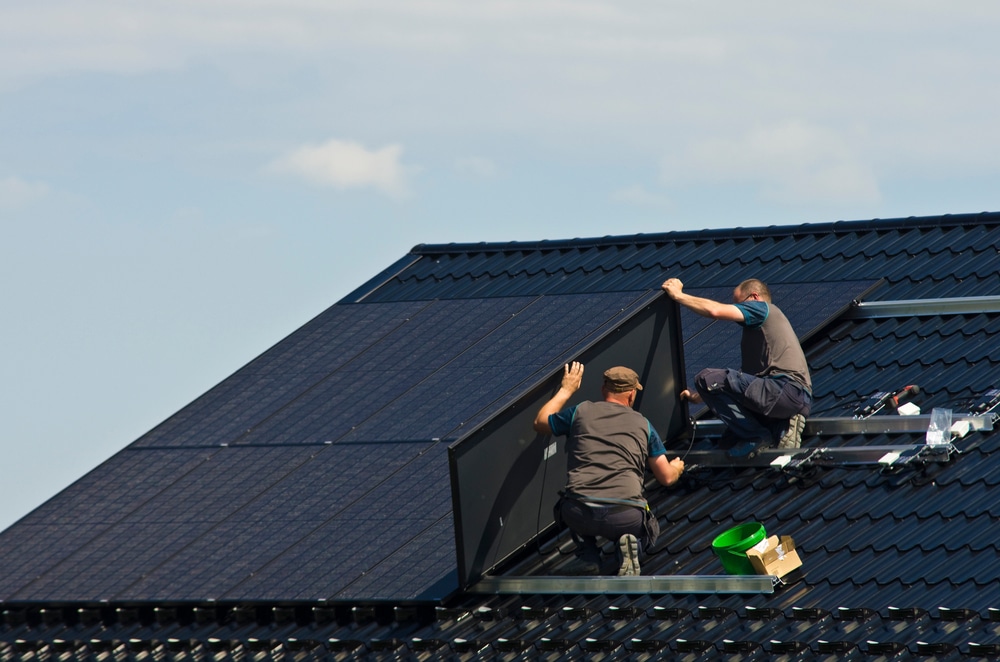 Black solar panels being installed by two men